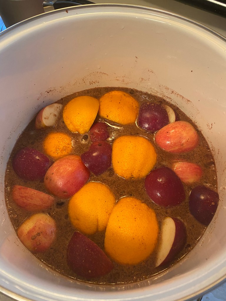 a pot of simmering apples and oranges and spices to make cider